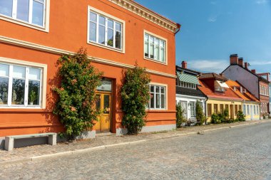 İsveç 'in güney ucundaki Ystad' da bir kaldırım taşı sokağının güzel yaz manzarası. Renkli evlerin duvarında büyüyen gül çalıları yaz güneşinde ve mavi gökyüzünde.