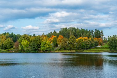 İsveç 'teki mezarlık nehrin diğer tarafında, yemyeşil ve sonbahar renkli ağaçlarla çevrili.