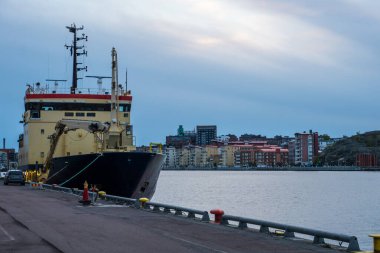 Göteborg Limanı 'na demirli siyah ve sarı kargo gemisi. Arka planda şehrin güzel bir manzarası var.