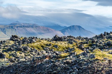 İzlanda 'nın batı kesiminde bir lav tarlası ve bir dağ sırasına bakın.