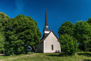 Brunneby, İsveç 'teki çok eski beyaz kilise, 12. yüzyıldan kalma. Güneşli, mavi gökyüzü ve yemyeşil ağaçlarla dolu güzel bir yaz gününde