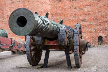 Tahta tekerleklerin üzerinde duran büyük ağızlıklı antika pirinç top.