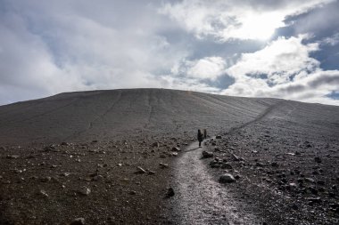 İzlanda 'daki çok yüksek bir volkanın tepesindeki kratere doğru yürüyen insanlar. Güzel güneşli bir günde bulutlu mavi gökyüzü