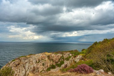 İsveç 'in güney batı kıyısındaki kayalıklardan gün ışığına bak. Şiddetli yağmurlar yağarken okyanus üzerindeki kara yağmur bulutları