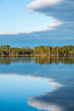 İsveç 'te bir göl boyunca güzel bir yaz manzarası bulutlar ve durgun sulara yansıyan mavi gökyüzü.