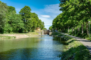 İsveç 'teki Gota Kanalı' nda deniz kilitlenmesi güzel, güneşli bir yaz günü nehir kıyısı boyunca yemyeşil ağaçlarla