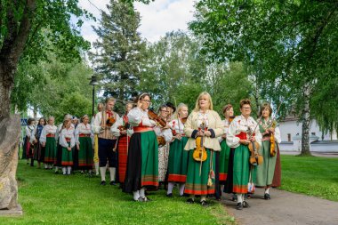 Geleneksel olarak giyinmiş İsveçli folk müzisyenlerinin geçit töreni, İsveç 'in Orsa şehrinde yaz ortasını kutlamak için yürüyüş