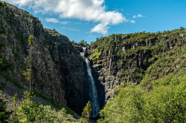 Kuzey İsveç 'teki ünlü Njupeskar şelalesinin güzel yaz manzarası. Parlak güneş ışığı ve sifon suyuyla.