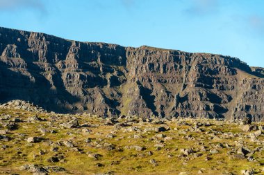Volkanik İzlanda manzarasının engin manzarası, kayalarla dolu yaz manzarası bir dağ duvarında bitiyor.