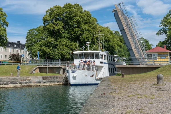 İsveç 'in Motala kentindeki Gota kanalında dar bir köprüden geçen turistlerle dolu bir tur teknesi. Güzel bir yaz gününde.