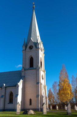 İsveç, Stjarnsund 'daki güzel beyaz kilise. Açık mavi gökyüzüne, güneşe ve sonbahar renkli ağaçlara karşı