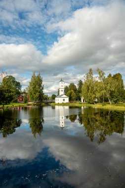 İsveç 'in Stjarnsund şehrinde yeşil bitki örtüsüyle çevrili güzel bir itfaiye binası ya da gözetleme kulesi. Parlak yaz güneşinde, öndeki sakin suda yansıyor.