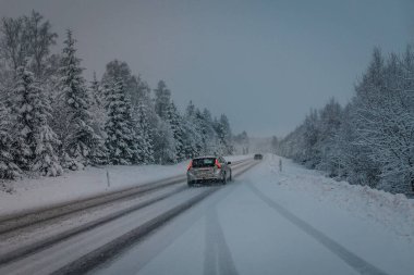 İsveç 'te kış yolu akşam vakti alçak ışıkta, arabalar çamurda ve karda geçiyor.