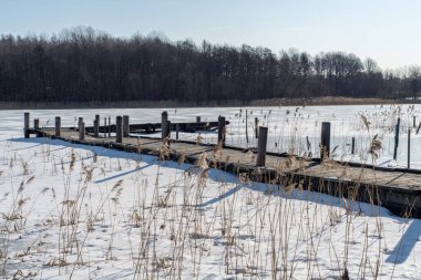 Küçük tekneler için eski ahşap iskele. Donmuş ve buza sıkışmış. Kuzey İsveç 'te dondurucu bir kış gününde parlak güneş ve mavi gökyüzü