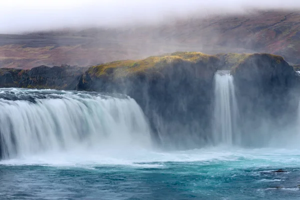 トルコ石色の水が秋の色の山の中腹に流れるアイスランドの美しい滝 — ストック写真