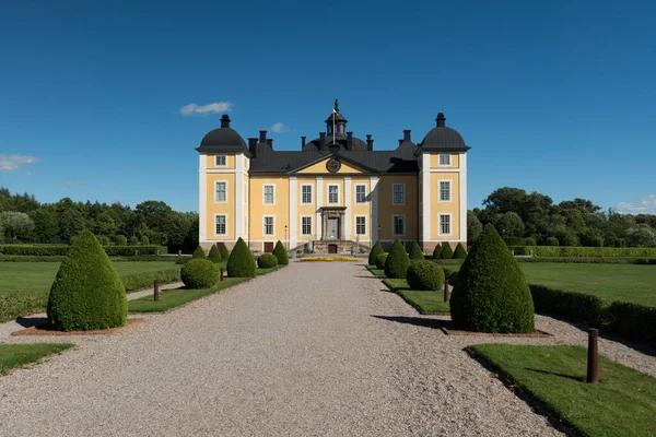 İsveç 'teki güzel Stromsholm kalesi, parlak sarı güneş ışığı ve mavi gökyüzü.