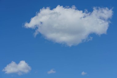 Mavi bir gökyüzünden beyaz tüylü bulutlar ve güneş ışığı.