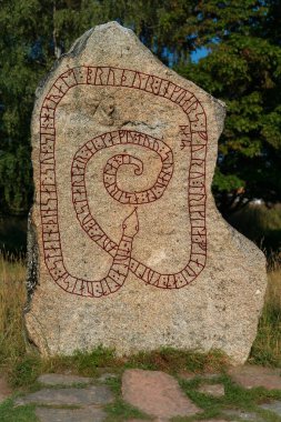 Vikingler zamanından kalma eski bir runik taş. Üzerinde kırmızı yılan şeklinde rünler var.