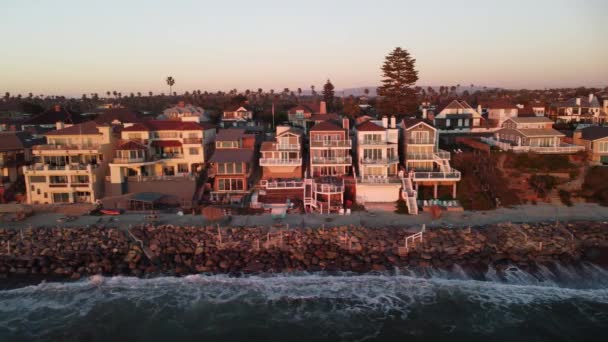 南カリフォルニアの海岸線の4K空中ビュードローンショット 青い太平洋で波が来て美しい夕日にはバックグラウンドで素敵な家 — ストック動画