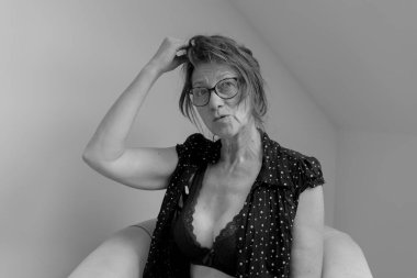 Evde güzel bir dekoltesi olan ve kitap okuyan siyah beyaz giyimli çekici olgun kadınlar.