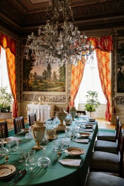 Vranov nad dyji, Güney Moravya, Çek Cumhuriyeti, 03 Temmuz 2021: Barok ahşap oymalı mobilyalar, boyalı duvarlı yemek odası, porselen servis ve masa üzerinde kristal bardaklar.