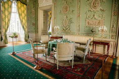 Vranov nad dyji, Güney Moravya, Çek Cumhuriyeti, 03 Temmuz 2021: Kale içi, barok ahşap oyma mobilya, yeşil misafir salonu, boyalı duvarlar, masada porselen servis, kristal avize.