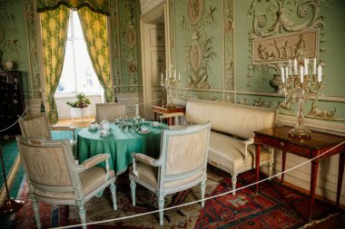 Vranov nad dyji, Güney Moravya, Çek Cumhuriyeti, 03 Temmuz 2021: Kale içi, barok ahşap oyma mobilya, yeşil misafir salonu, boyalı duvarlar, masada porselen servis, kristal avize.