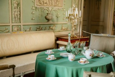 Vranov nad dyji, Güney Moravya, Çek Cumhuriyeti, 03 Temmuz 2021: Kale içi, barok ahşap oyma mobilya, yeşil misafir salonu, boyalı duvarlar, masada porselen servis, kristal avize.