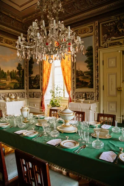 Vranov nad dyji, Güney Moravya, Çek Cumhuriyeti, 03 Temmuz 2021: Barok ahşap oymalı mobilyalar, boyalı duvarlı yemek odası, porselen servis ve masa üzerinde kristal bardaklar.