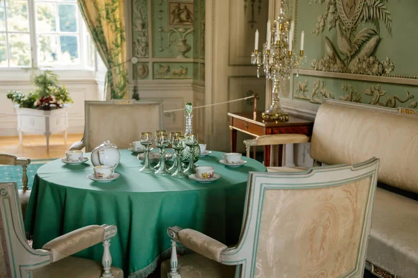 Vranov nad dyji, Güney Moravya, Çek Cumhuriyeti, 03 Temmuz 2021: Kale içi, barok ahşap oyma mobilya, yeşil misafir salonu, boyalı duvarlar, masada porselen servis, kristal avize.