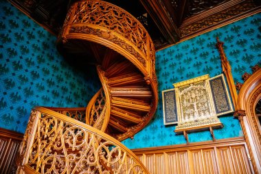 Lednice, Güney Moravya, Çek Cumhuriyeti, 04 Temmuz 2021: Neo-gotik romantik ahşap oymalı mobilyalar, mavi şato kütüphanesinde çiçeklerle süslenmiş dekoratif spiral merdivenler.