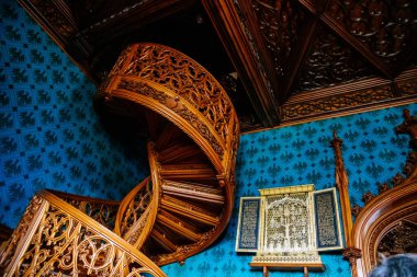 Lednice, Güney Moravya, Çek Cumhuriyeti, 04 Temmuz 2021: Neo-gotik romantik ahşap oymalı mobilyalar, mavi şato kütüphanesinde çiçeklerle süslenmiş dekoratif spiral merdivenler.