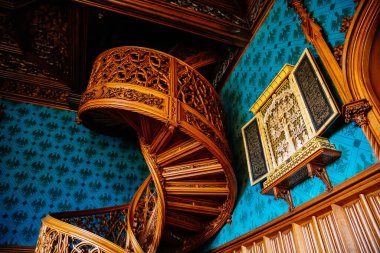 Lednice, Güney Moravya, Çek Cumhuriyeti, 04 Temmuz 2021: Neo-gotik romantik ahşap oymalı mobilyalar, mavi şato kütüphanesinde çiçeklerle süslenmiş dekoratif spiral merdivenler.