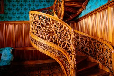 Lednice, Güney Moravya, Çek Cumhuriyeti, 04 Temmuz 2021: Neo-gotik romantik ahşap oymalı mobilyalar, mavi şato kütüphanesinde çiçeklerle süslenmiş dekoratif spiral merdivenler.