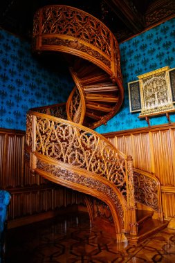 Lednice, Güney Moravya, Çek Cumhuriyeti, 04 Temmuz 2021: Neo-gotik romantik ahşap oymalı mobilyalar, mavi şato kütüphanesinde çiçeklerle süslenmiş dekoratif spiral merdivenler.