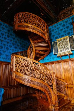 Lednice, Güney Moravya, Çek Cumhuriyeti, 04 Temmuz 2021: Neo-gotik romantik ahşap oymalı mobilyalar, mavi şato kütüphanesinde çiçeklerle süslenmiş dekoratif spiral merdivenler.