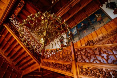 Lednice, Güney Moravya, Çek Cumhuriyeti, 04 Temmuz 2021: Neo-gotik ahşap oymalı mobilyalar, salondaki dekoratif merdivenler, çiçek süsleri, mumlu şamdan.