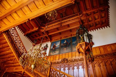 Lednice, Güney Moravya, Çek Cumhuriyeti, 04 Temmuz 2021: Neo-gotik ahşap oymalı mobilyalar, salondaki dekoratif merdivenler, çiçek süsleri, mumlu şamdan.