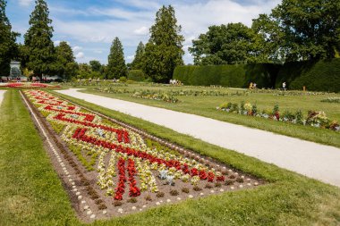 Lednice, Güney Moravya, Çek Cumhuriyeti, 04 Temmuz 2021: Güzel bahçeli şato, güneşli yaz gününde yeşil parklar, neo-gotik romantik kale, geometrik çiçek yatağı, Lednice Valtice Peyzajı.