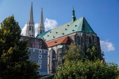 Goerlitz, Almanya, 04 Eylül 2021: Gotik ortaçağ St. Peter ve Paul Kilisesi veya Peterskirche, güneşli yaz gününde şehrin merkezinde iki beyaz kuleli, Lusatian Neisse 'li Neisbank..