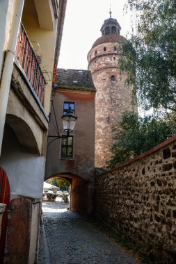 Goerlitz, Saksonya, Almanya, 04 Eylül 2021: Gotik rönesans devasa Nikolaiturm veya Nikolai Kulesi, eski şehrin tarihi merkezi, ortaçağ tahkimatının bir parçası, güneşli yaz gününde dar bir cadde.