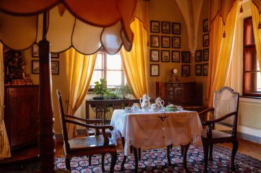 Cervena Lhota, Güney Bohemya, Çek Cumhuriyeti, 9 Ekim 2021: Kale içi, barok ahşap mobilya, misafir salonu, masada porselen çay servisi, pencerenin karşısındaki sandalyeler, tablolar 