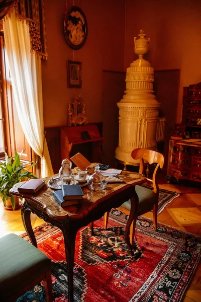 Cervena Lhota, Güney Bohemya, Çek Cumhuriyeti, 9 Ekim 2021: Barok ahşap oymalı mobilyalar, yatak odası, kitaplı masa, porselen çay seti ve kağıt kaplama vantilatörü, seramik seramik seramik seramikli ocak