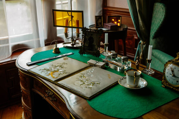 Червена-Лота, Южная Чехия, 9 октября 2021 года: интерьер замка с барочной деревянной резной мебелью, кабинет, стол, покрытый зеленой тканью, письменные принадлежности, свечи и портрет 