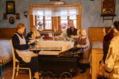 Prerov nad Labem, Çek Cumhuriyeti, 5 Aralık 2021: Geleneksel köy evi, çocuklu aile, Skanzen 'de Noel, Polabi açık hava etnoğrafya müzesi, seramik çinili ocak