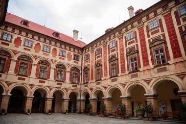 Libochovice, Bohemya, Çek Cumhuriyeti, 19 Eylül 2021: Fransız tarzı park ve bahçeli kale, Romantik kırmızı ve sarı barok şato, sonbahar günü atari salonlu avlu, seramik kaplarda bitkiler