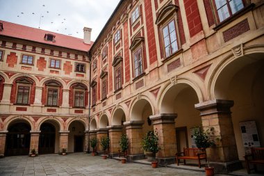 Libochovice, Bohemya, Çek Cumhuriyeti, 19 Eylül 2021: Fransız tarzı park ve bahçeli kale, Romantik kırmızı ve sarı barok şato, sonbahar günü atari salonlu avlu, seramik kaplarda bitkiler