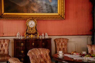 Libochovice, Bohemia, Çek Cumhuriyeti, 19 Eylül 2021: Barok ahşap mobilyalar, çekmeceli şifoniyerde altın kaplama antika saat, duvarda altın çerçeveli resim