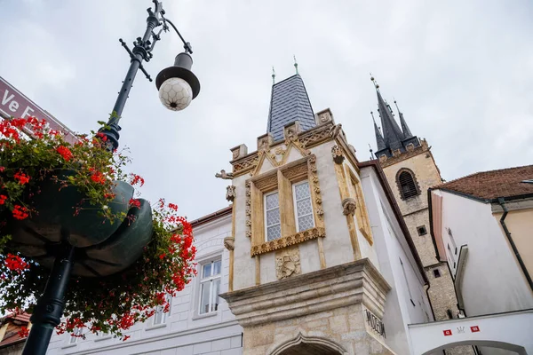 Louny, Çek Cumhuriyeti, 19 Eylül 2021: Mor Şahinleri Evi Bölge Müzesi, Gotik görünüşlü tarihi kasaba binası, güneşli bir sonbahar gününde Aziz Niklas Kilisesi 'nin kulesi