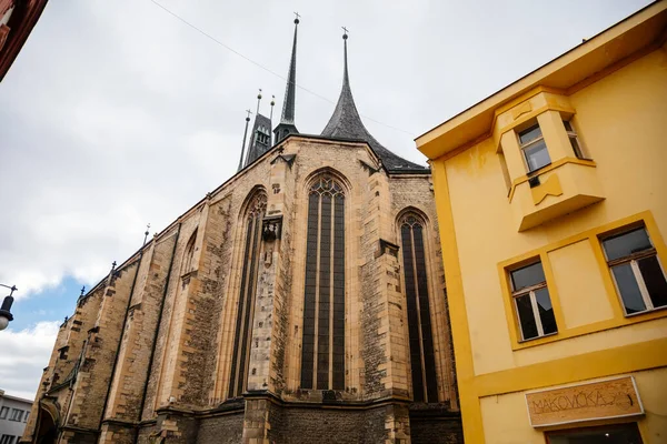 Louny, Çek Cumhuriyeti, 19 Eylül 2021: Gotik yüksek saat kulesine sahip Ortaçağ Katolik taş kilisesi, tarihi şehir merkezinde dar resimli cadde, kemerler 